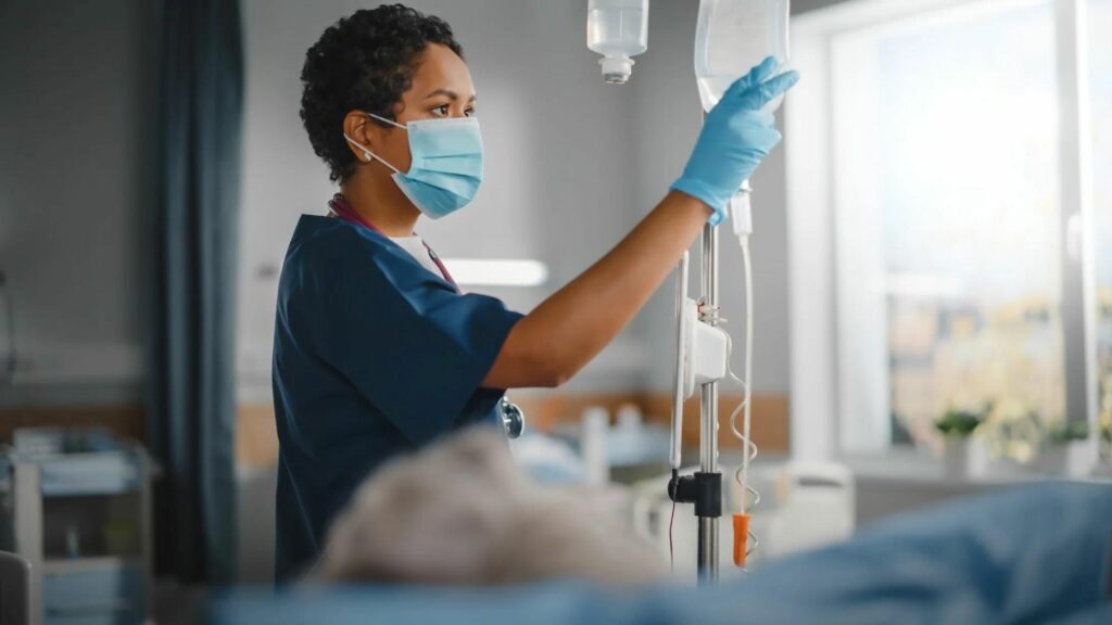 A Nurse Fixing a Drip in a Hospital Ward